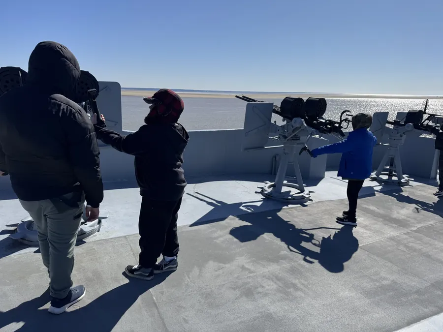 Scouts trying out the anti-aircraft gun mounts on a bright morning, looking out over Mobile Bay.